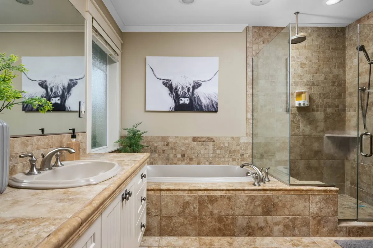 A luxurious bathroom with a freestanding bathtub, a spacious shower area, a vanity with sink, and framed artwork, creating a tranquil, spa-like atmosphere for relaxation and rejuvenation.