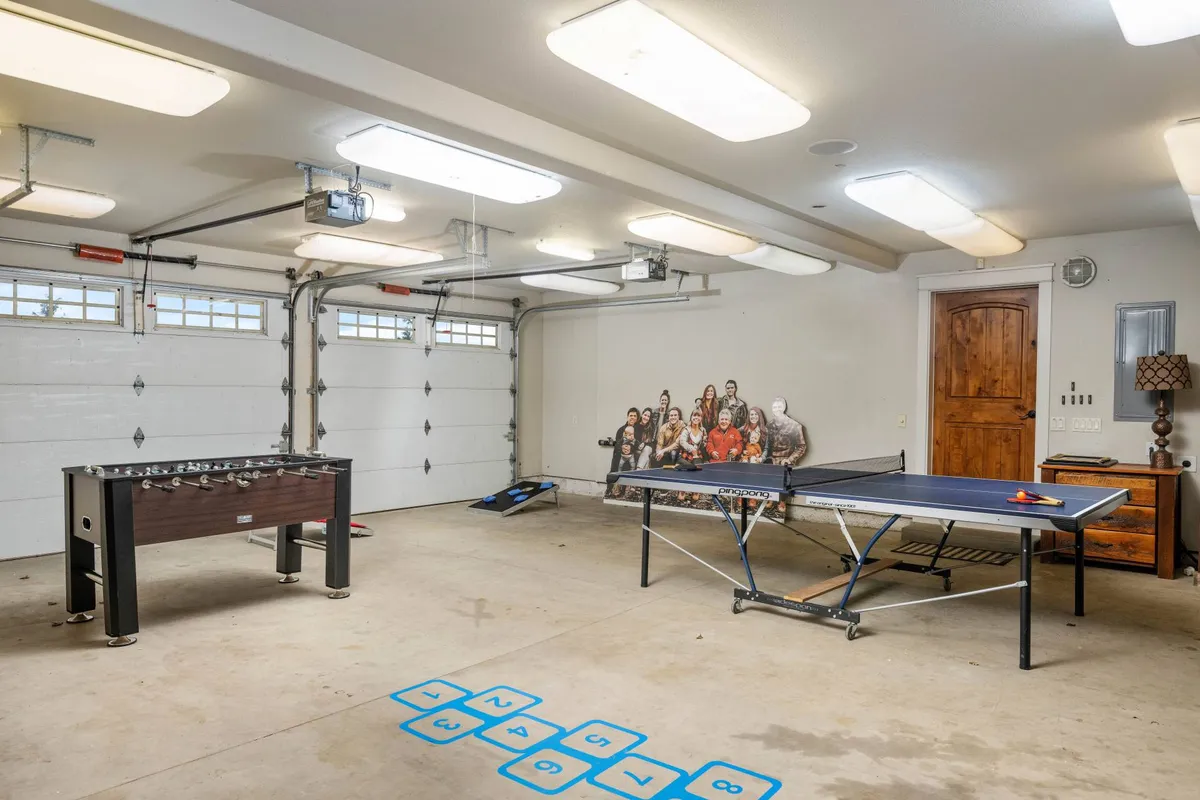 A vibrant interior view of a game space with both a ping pong table and a foosball table, enhanced by decorative wall art and colorful game floor tiles. The energetic setup is ideal for group tournaments or family fun nights.