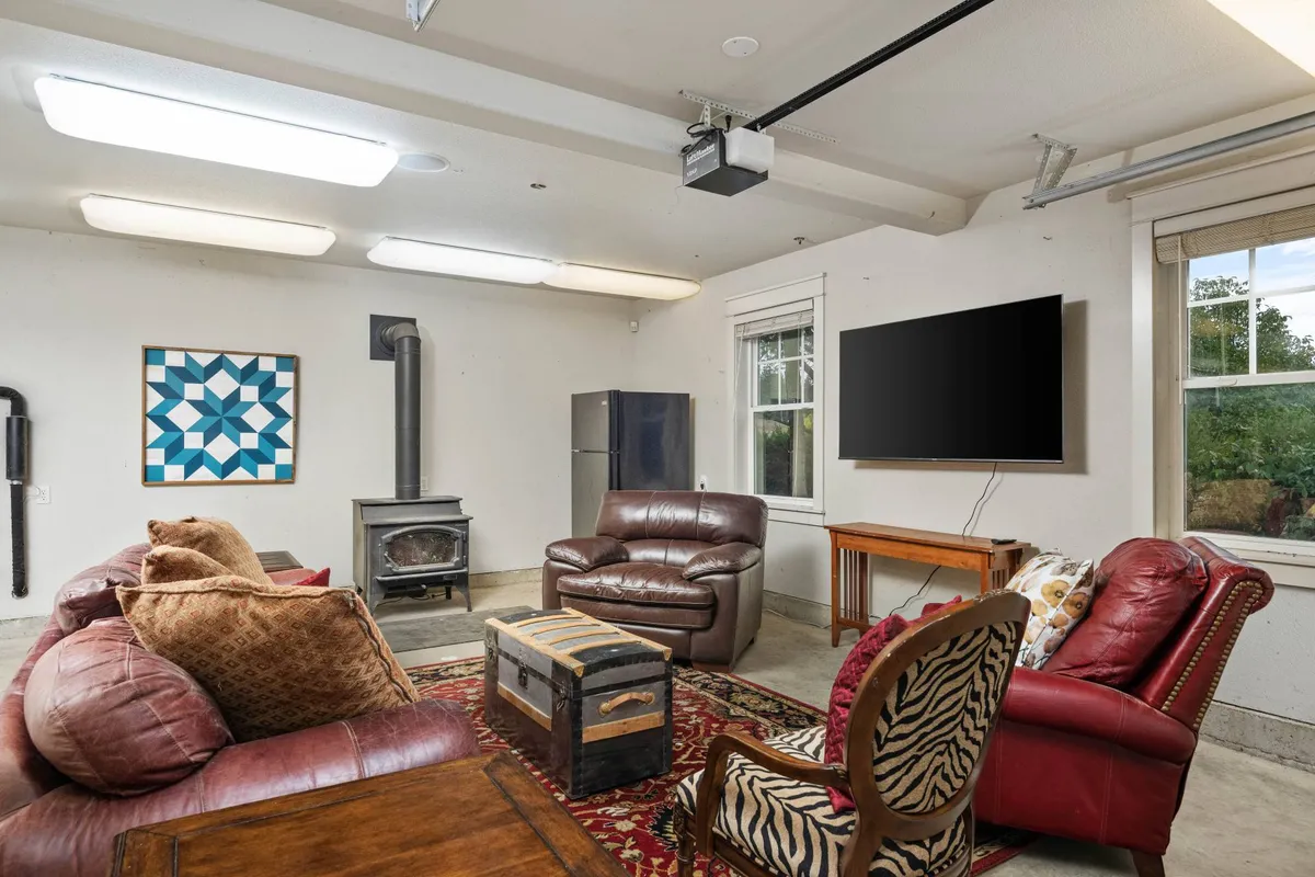 A comfortable living area with leather sofas, a wooden coffee table, colorful wall art, a wood stove, and a large TV—perfect for gatherings, casual meetings, or entertainment. The overall mood is warm and inviting, suggesting a versatile, multi-purpose room.