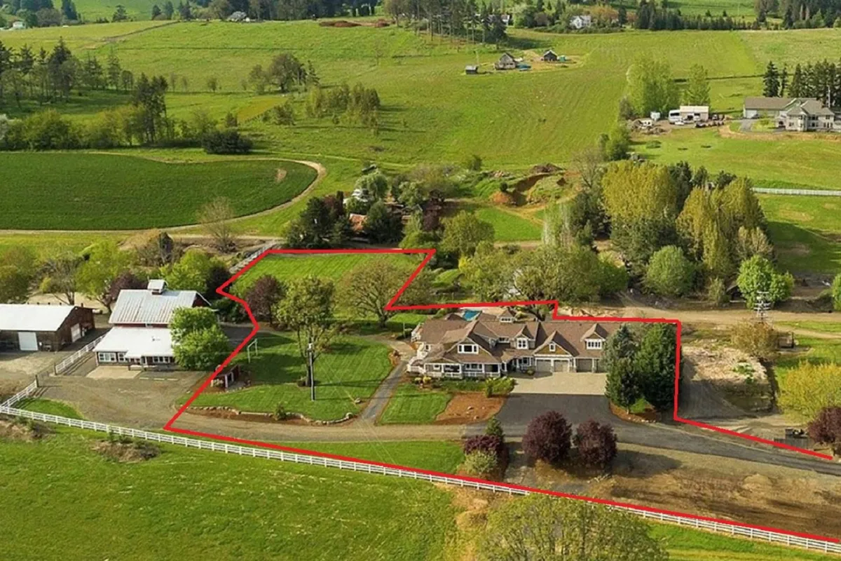 A panoramic exterior shot showing the main house, the iconic barn, open fields, and mature trees along the driveway. The golden hour lighting enhances the peaceful, rural atmosphere and underscores the scale and beauty of the farm.